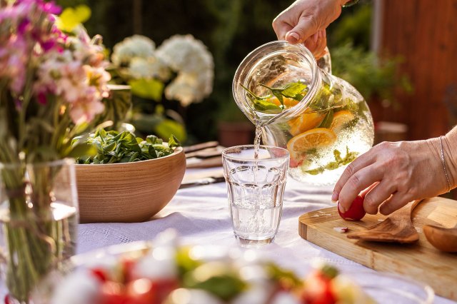 An image of water being poured into a glass on an outdoor dinner table