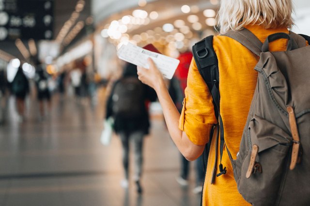 Woman holds airplane ticket while walking through airport