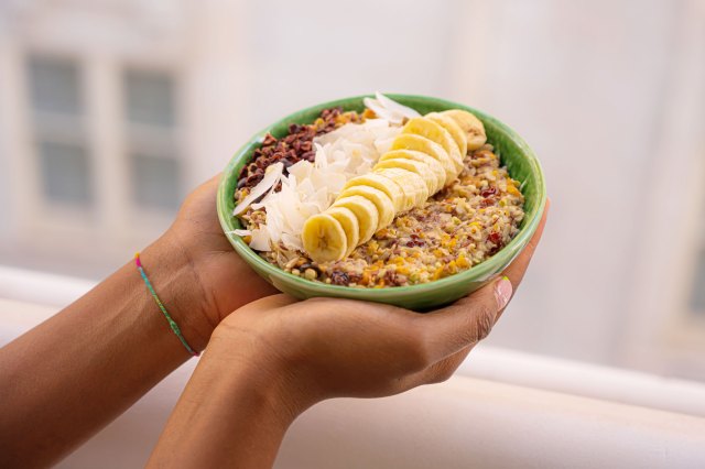 An image of hands holding a green bowl of oatmeal