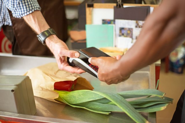 Hands exchanging a card reader over fresh vegetables