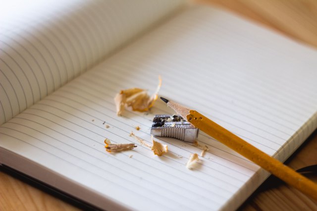 A pencil, pencil sharpener, and pencil shavings on the page of an open book