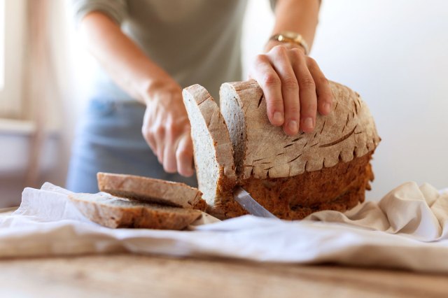 An image of a person slicing a loaf of bread