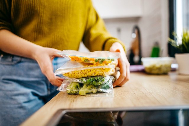 An image of a woman holding vegetables in zip-top bags