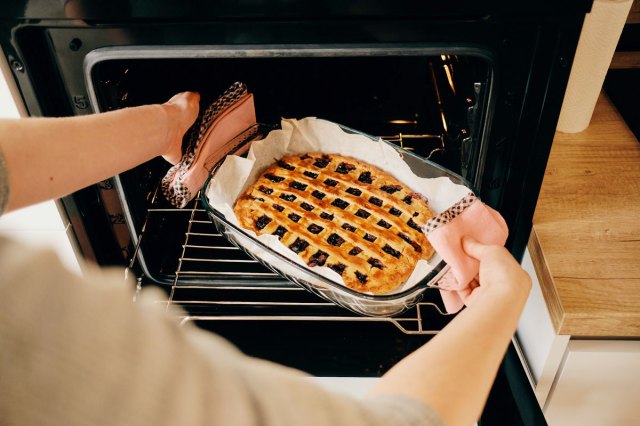 An image of a person pulling a pie out of the oven