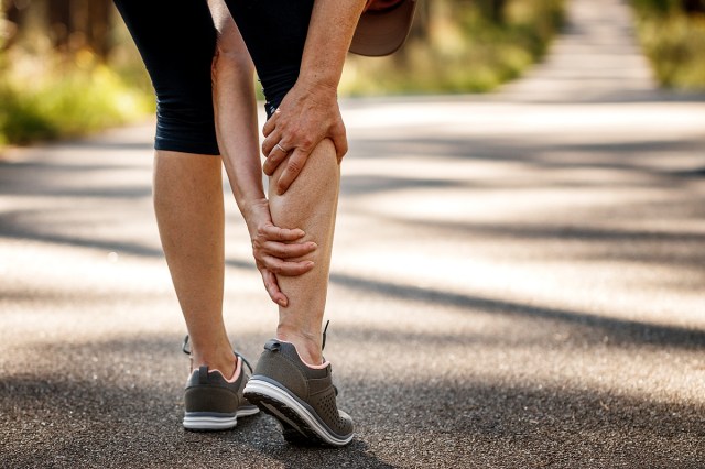An image of a person holding their calf while outside