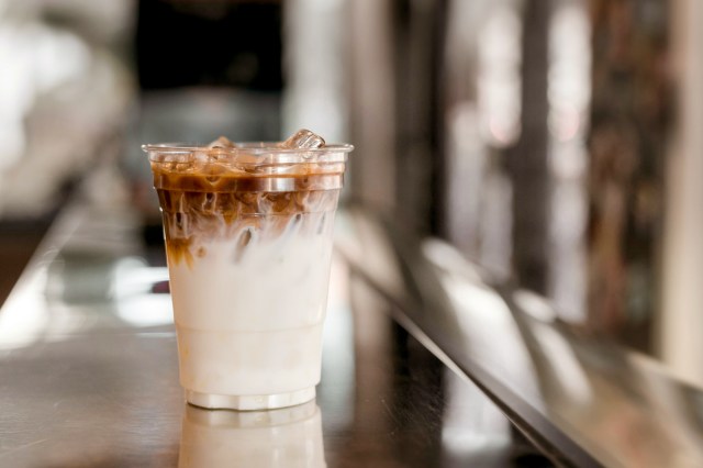 An image of a ice latte coffee in plastic glass on black table at cafe