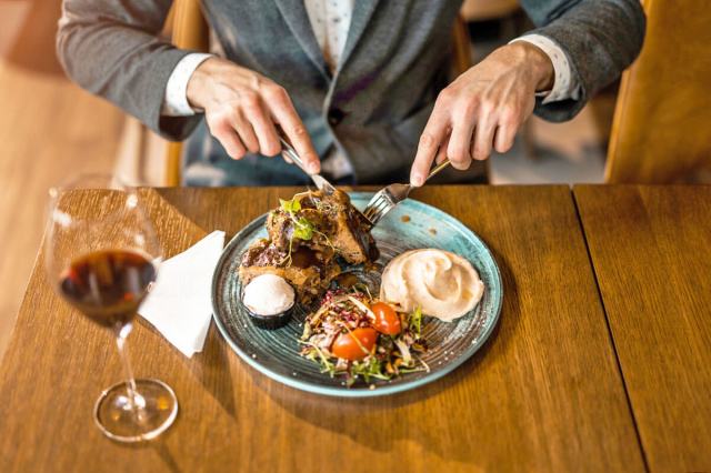 Person cutting into a meal on a plate before them